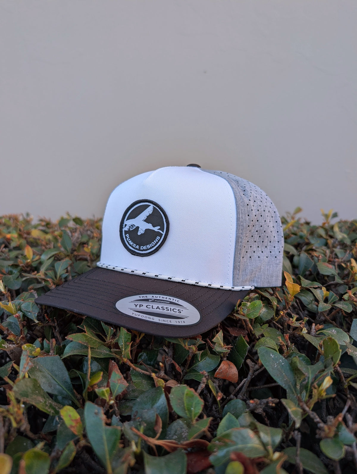 Puakea perforated rope hat with white front panel, black brim, gray perforated panels, and Puakea logo patch.