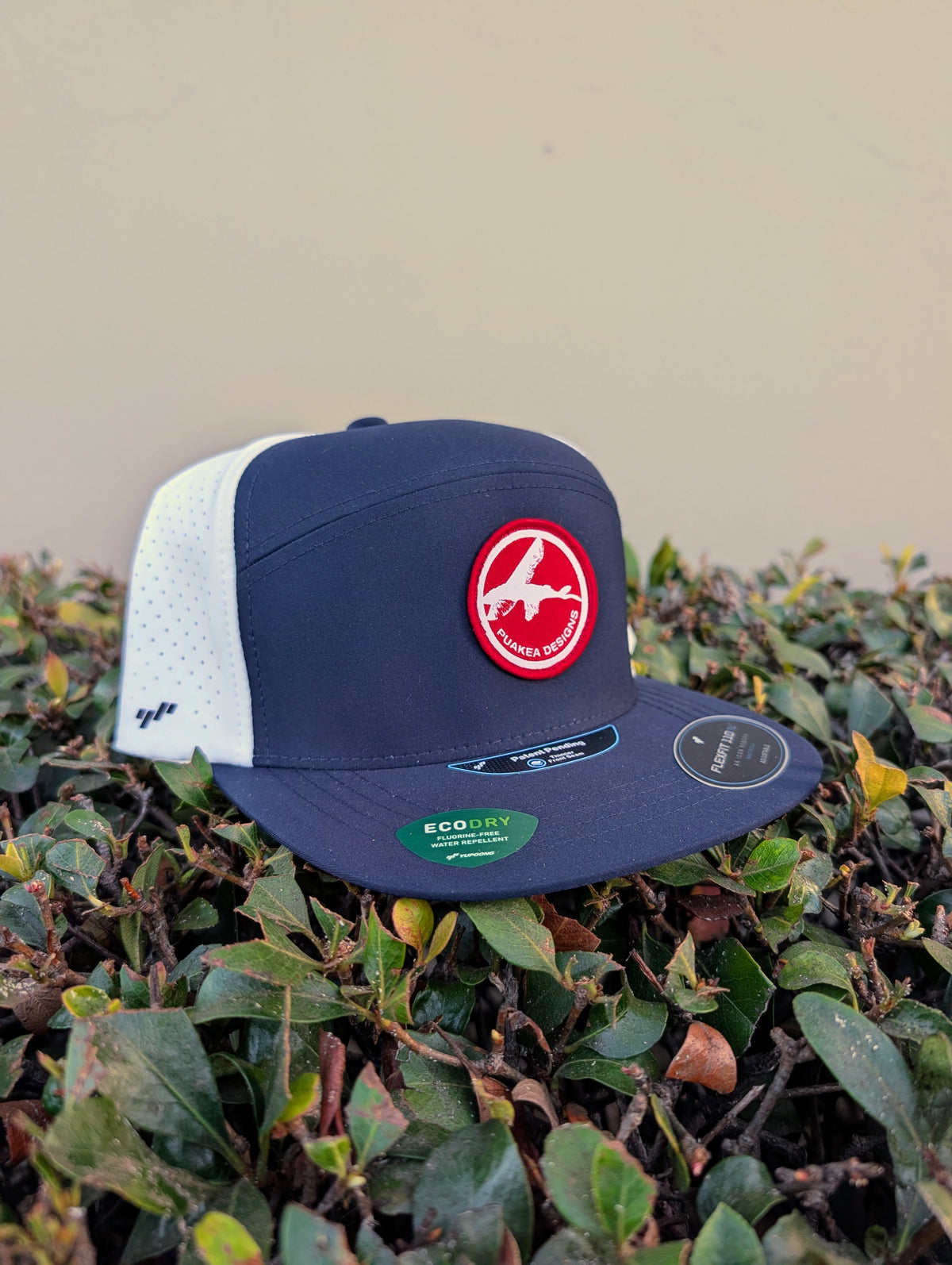 Navy and white Puakea perforated hat with flat navy brim, white perforated panels, and red-and-white logo patch.